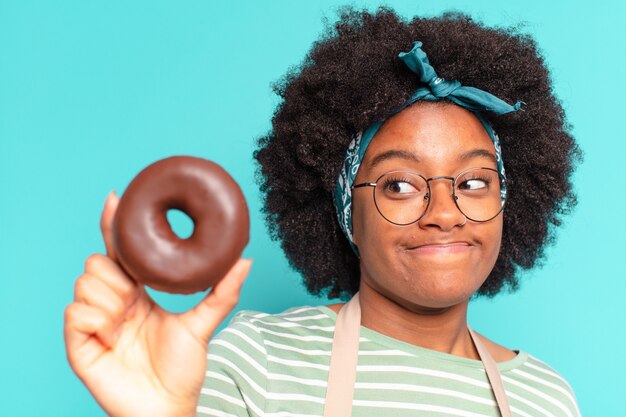 Foto jovem e linda mulher afro com uma rosquinha