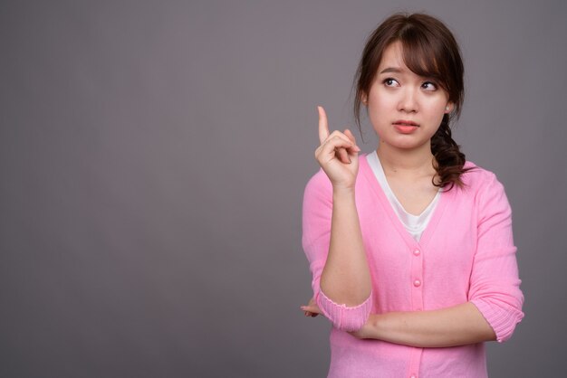 Jovem e linda mulher asiática vestindo camisa rosa