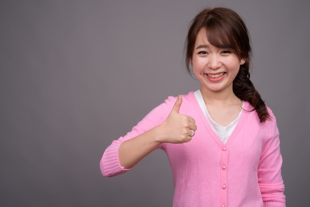 Jovem e linda mulher asiática vestindo camisa rosa