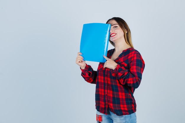 Jovem e linda mulher cobrindo o olho com a pasta em uma camisa casual, jeans