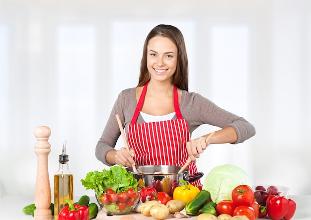 Jovem e linda mulher cozinhando legumes frescos