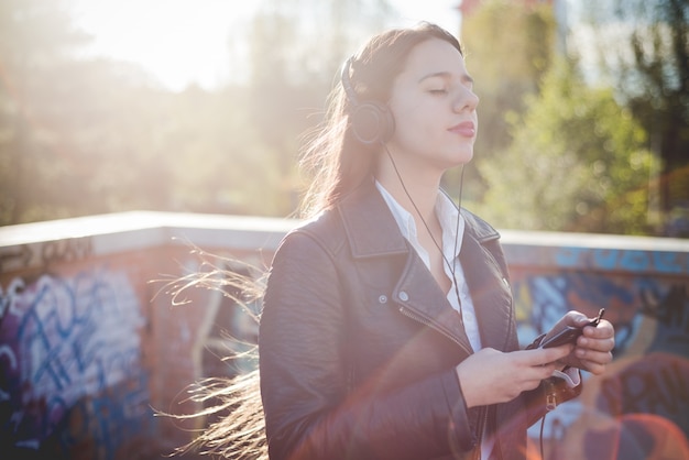 jovem e linda mulher de cabelo comprido ouvindo música na cidade