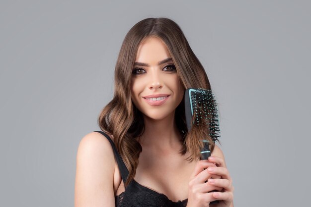 Jovem e linda mulher penteando o cabelo castanho Cuidados com o Cabelo Linda morena penteando o cabelo com h