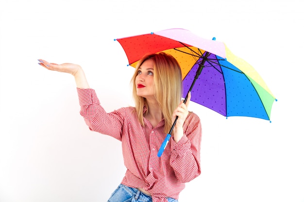 Jovem e linda mulher segurando um guarda-chuva colorido em branco