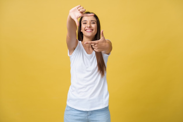 Jovem e linda mulher sobre fundo amarelo isolado sorrindo fazendo moldura