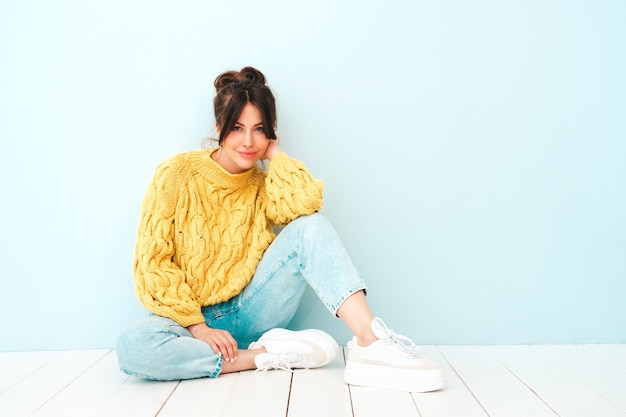 Jovem e linda mulher sorridente em jeans e suéter amarelo moderno de verão