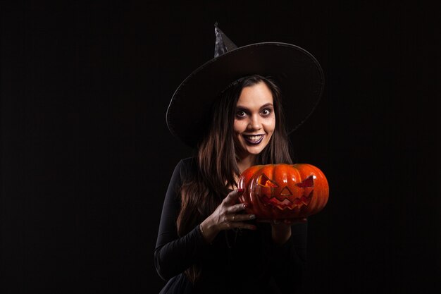 Foto de Lindo Sorrindo Bruxa De Halloween Segurando Um Jack O Lanterna Bela  Jovem De Chapéu De Bruxas E Traje Segurando A Abóbora Sobre Fundo Branco e  mais fotos de stock de