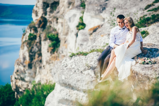 jovem e lindo casal posando sobre a rocha perto do lago