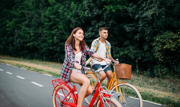 Jovem e mulher andando em bicicletas retrô