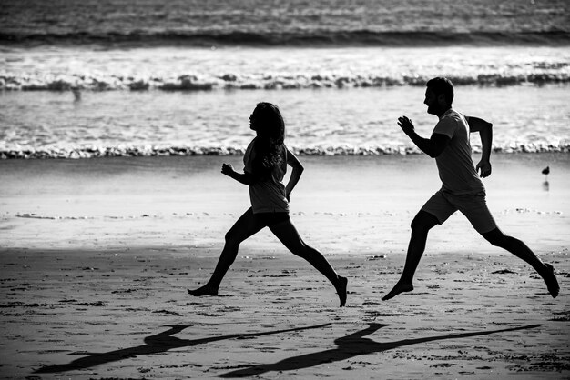 Jovem e mulher correndo correndo ao longo do mar Casal correndo na praia