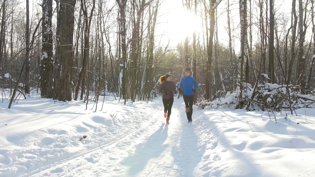 Jovem e mulher correndo na floresta de inverno