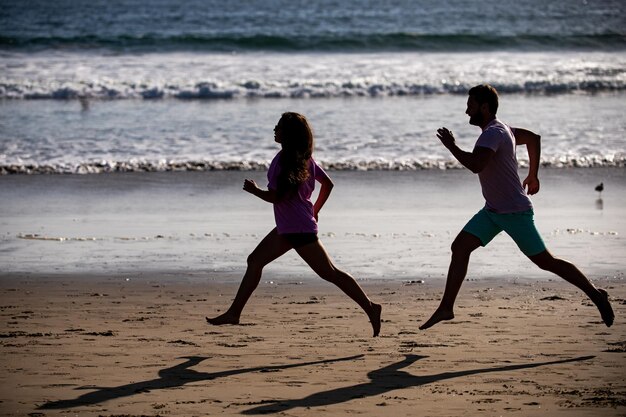 Jovem e mulher correndo para correr ao longo do mar. Casal correndo na praia.