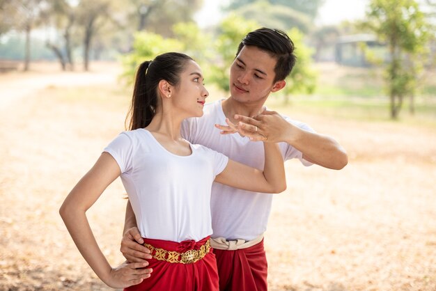 Jovem e mulher praticando uma dança tradicional tailandesa