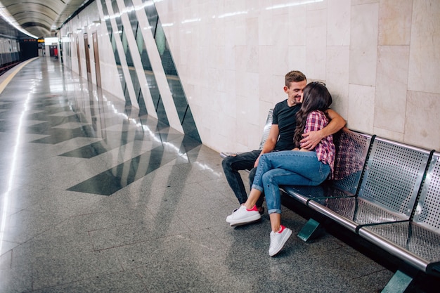 Jovem e mulher usam no subsolo. casal no metrô. mulher e jovem adorável sentar juntos. ele a abraça e beija. amor à primeira vista. vista urbana.