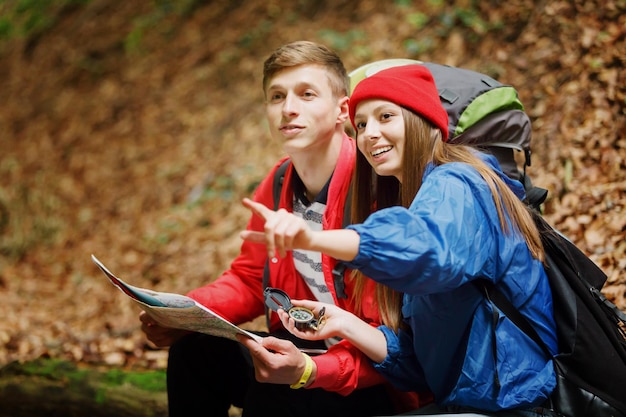 Jovem e mulher usando mapa para localizar e navegar enquanto mochila na floresta no verão