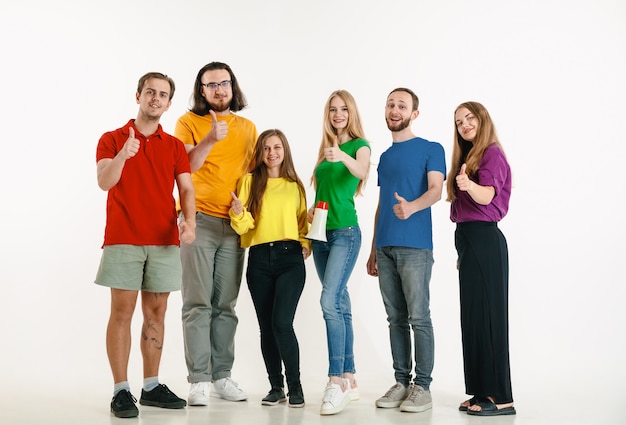 Jovem e mulher vestidos com as cores da bandeira lgbt na parede branca. modelos caucasianos com camisas brilhantes. pareçam felizes juntos, sorrindo e se abraçando. orgulho lgbt, direitos humanos e conceito de escolha.