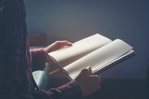 Jovem é sentado e lendo um livro.