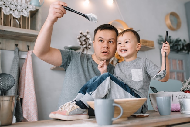 Jovem e seu filho brincando na cozinha