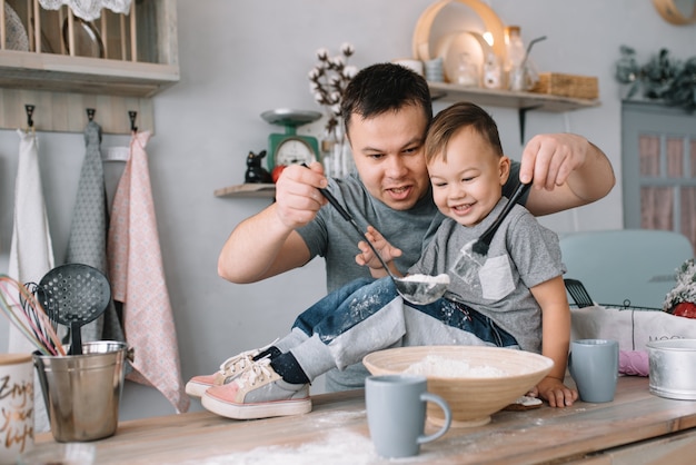 Jovem e seu filho brincando na cozinha