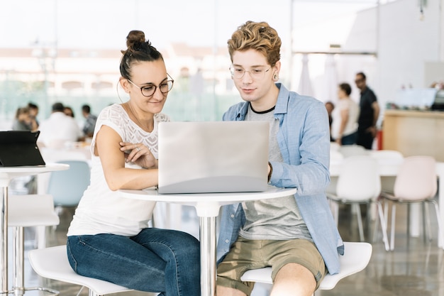 Jovem e uma garota trabalhando em conjunto com um laptop em um coworking