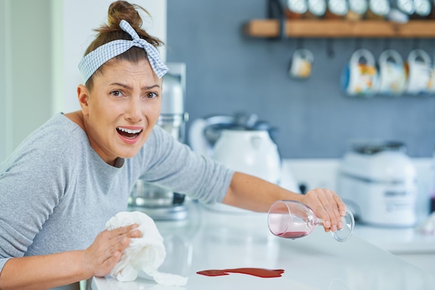 Jovem e vinho derramado na cozinha