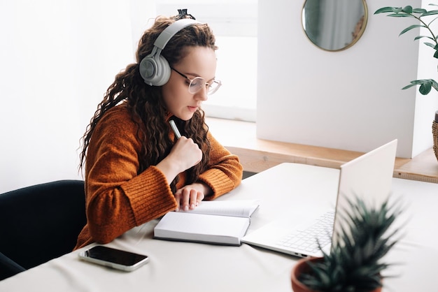 Jovem elearning em casa participando de aulas virtuais e reuniões de conferência remota no laptop Fem