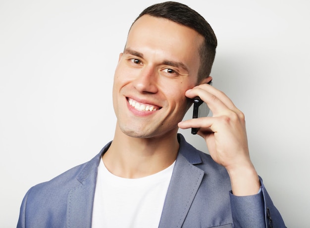 Jovem elegante a falar ao telemóvel sobre um fundo branco