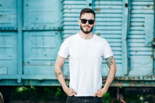 Jovem elegante com barba, usando uma camiseta branca e óculos