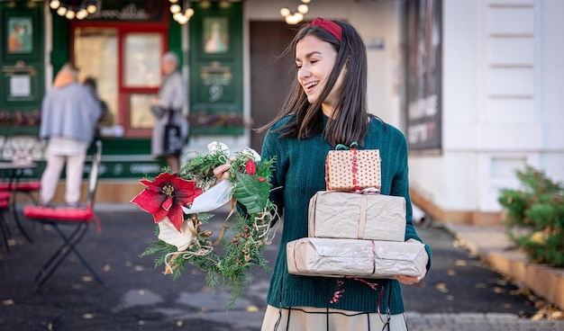 Jovem elegante com presentes de natal ao ar livre