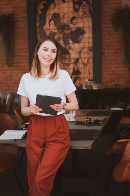 Jovem elegante com tablet digital trabalhando em um café de rua