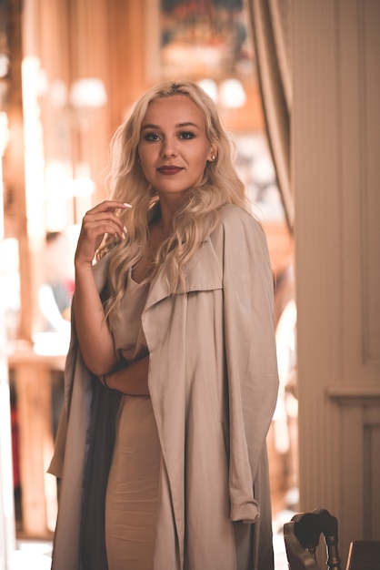 Foto jovem elegante com um vestido elegante bege e uma jaqueta em um café