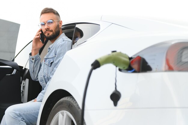 Foto jovem elegante é com carro elétrico durante o dia o conceito de energia verde