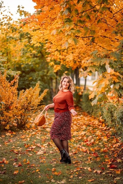 Jovem elegante e elegante caminha em um parque de outono Uma linda garota sorridente em um terno marrom em um fundo de folhas douradas