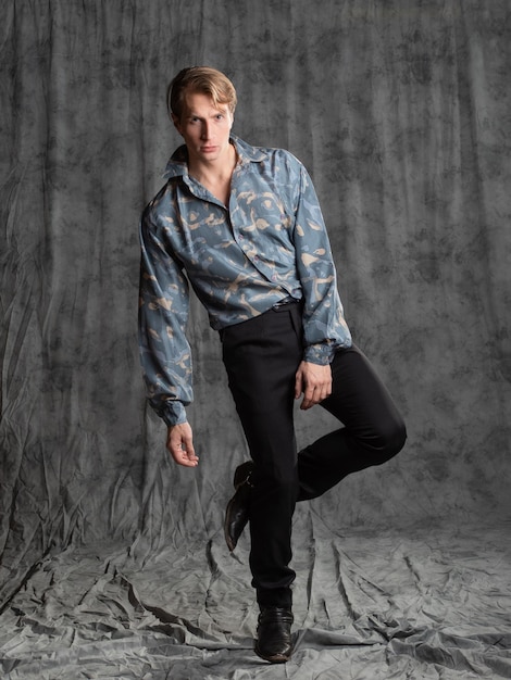 Jovem elegante e elegante com uma camisa de seda azul posando no estúdio em um fundo de tecido cinza
