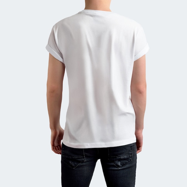 Jovem elegante em t-shirt branca em branco e calça jeans preta em um fundo branco do estúdio em branco. Vista traseira. O maquete pode ser usado em sua vitrine.