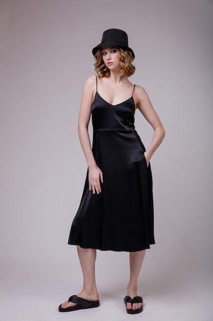 jovem elegante em um chapéu de vestido preto bonito posando sobre fundo cinza suave branco Studio Shot