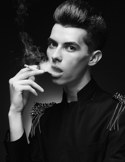 Jovem elegante fumando um cigarro. Tiro do estúdio.