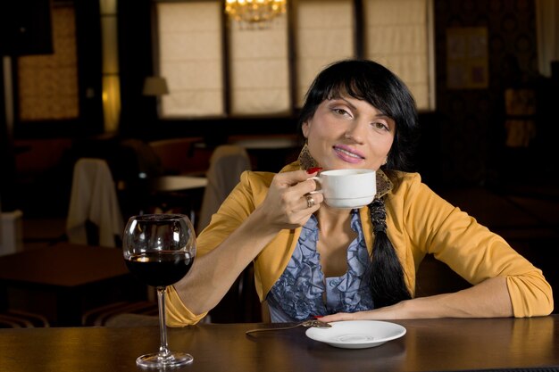 Jovem elegante relaxando tomando café no bar e fazendo uma pausa para sorrir para a câmera