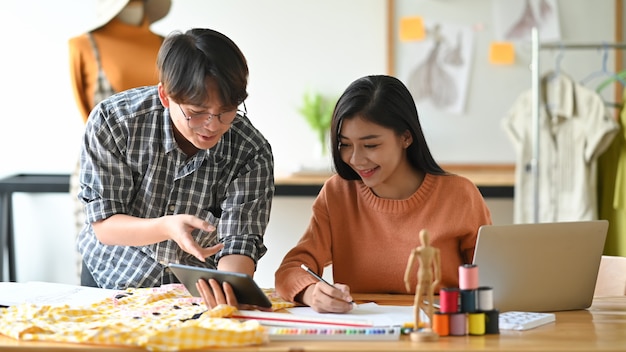 Jovem elegante reunião com esboço de designer de moda e planejamento com tablet digital.