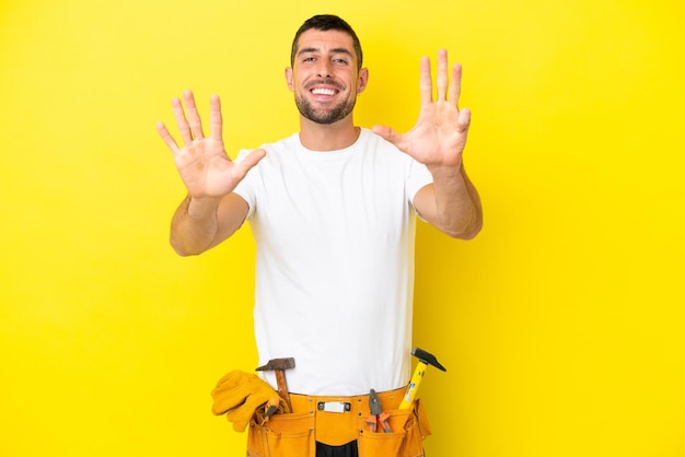 Jovem eletricista homem caucasiano isolado em fundo amarelo contando nove com os dedos