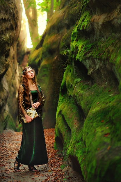 Foto jovem elfo feminino vagando na floresta segurando um livro antigo