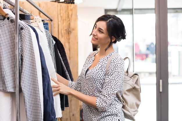 Foto jovem em boutique escolhendo roupas novas para comprar