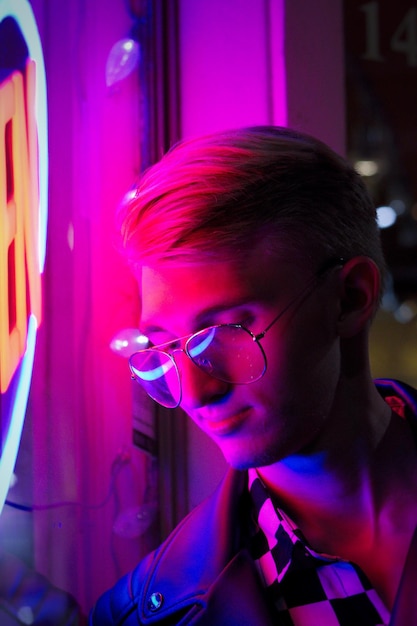Jovem em close-up usando óculos de pé perto de uma loja iluminada