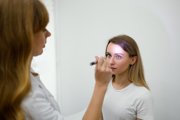 Jovem em consulta com neurologista Médica verifica os reflexos dos olhos com lanterna