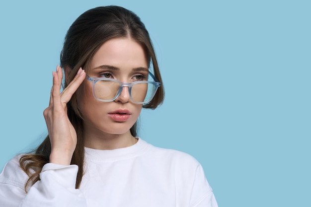 Jovem em elegantes óculos de armação azul isolados em fundo azul Visão Visão Moda