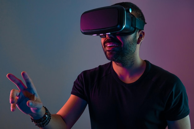 Jovem em fone de ouvido de óculos vr interage com a realidade virtual em cores neon light tecnologia futura ...