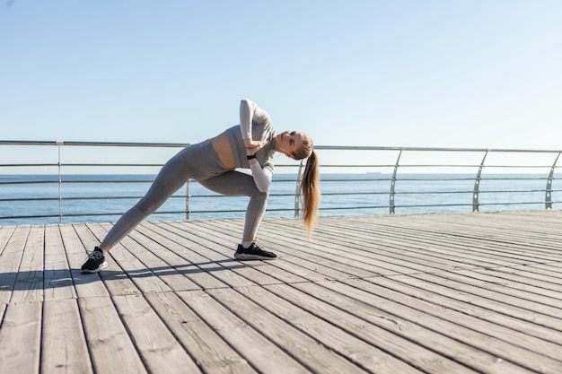 Jovem em forma de roupas esportivas pratica ioga asana pose na praia em um dia ensolarado