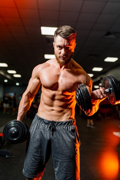 Jovem em forma levantando halteres fazendo exercícios em uma academia Esporte fitness levantamento de peso musculação treinamento atleta exercícios de treino conceito