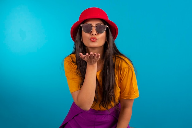 Jovem em foto de estúdio e em roupas coloridas e chapéu vermelho