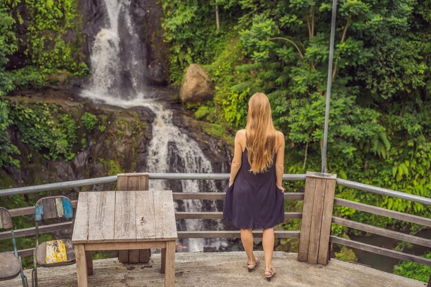 Jovem em frente à cachoeira Turista feminina olhando para a cachoeira